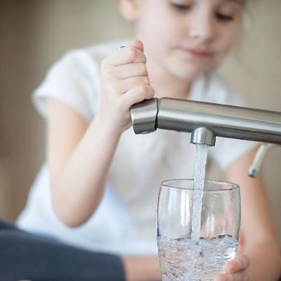 child fills a glass at a water tap